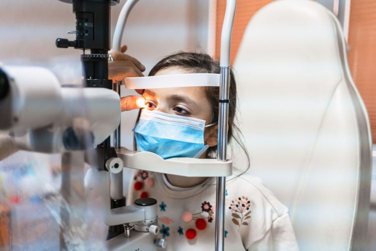 ophthalmologist is checking the eye vision of cute child in modern clinic